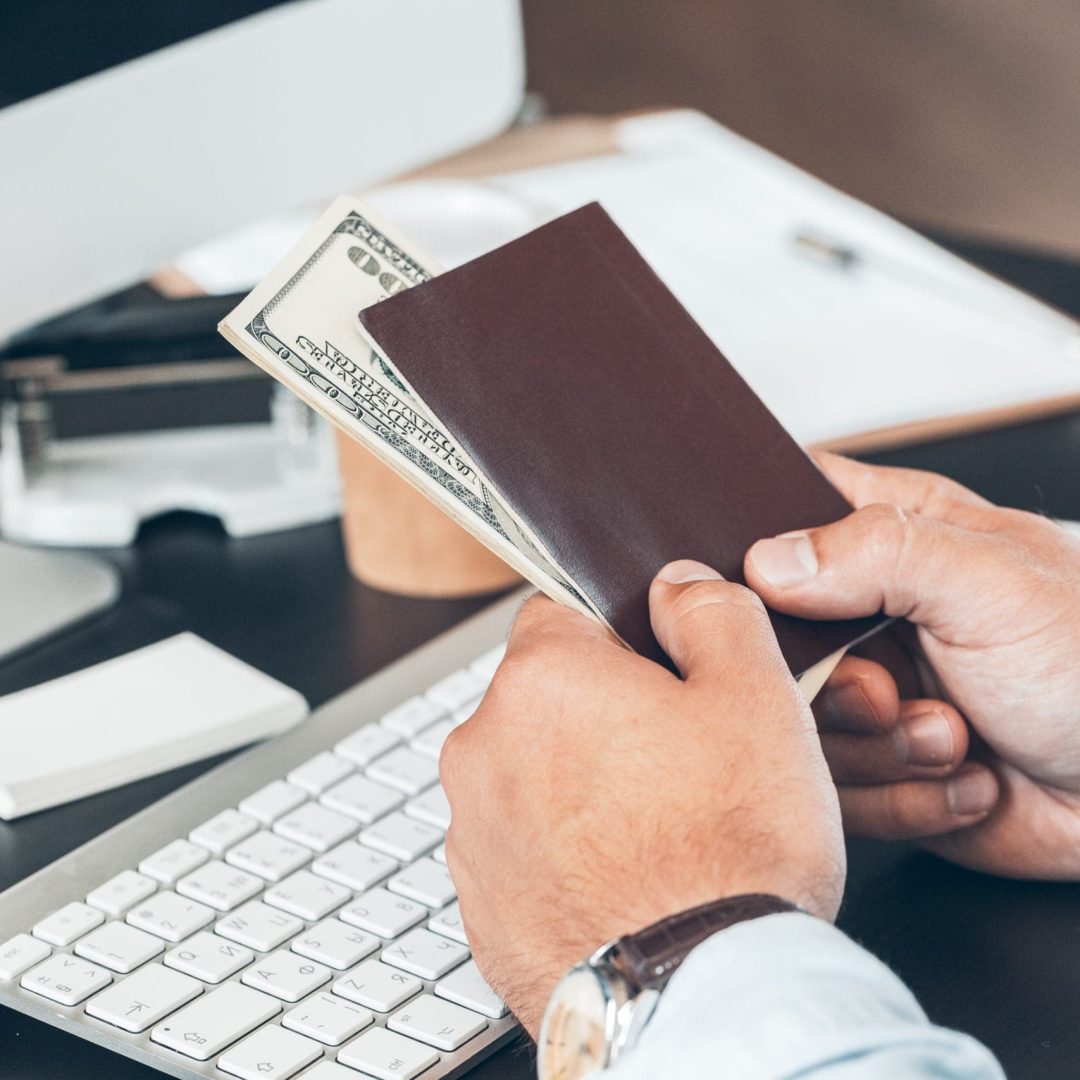 Close up of a businessman holding dollar banknotes and passport in his hands in office Close up of a businessman holding dollar banknotes and passport in his hands in office