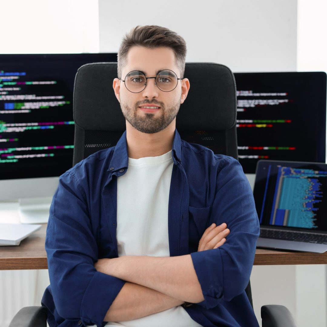 Happy young programmer working at desk in office