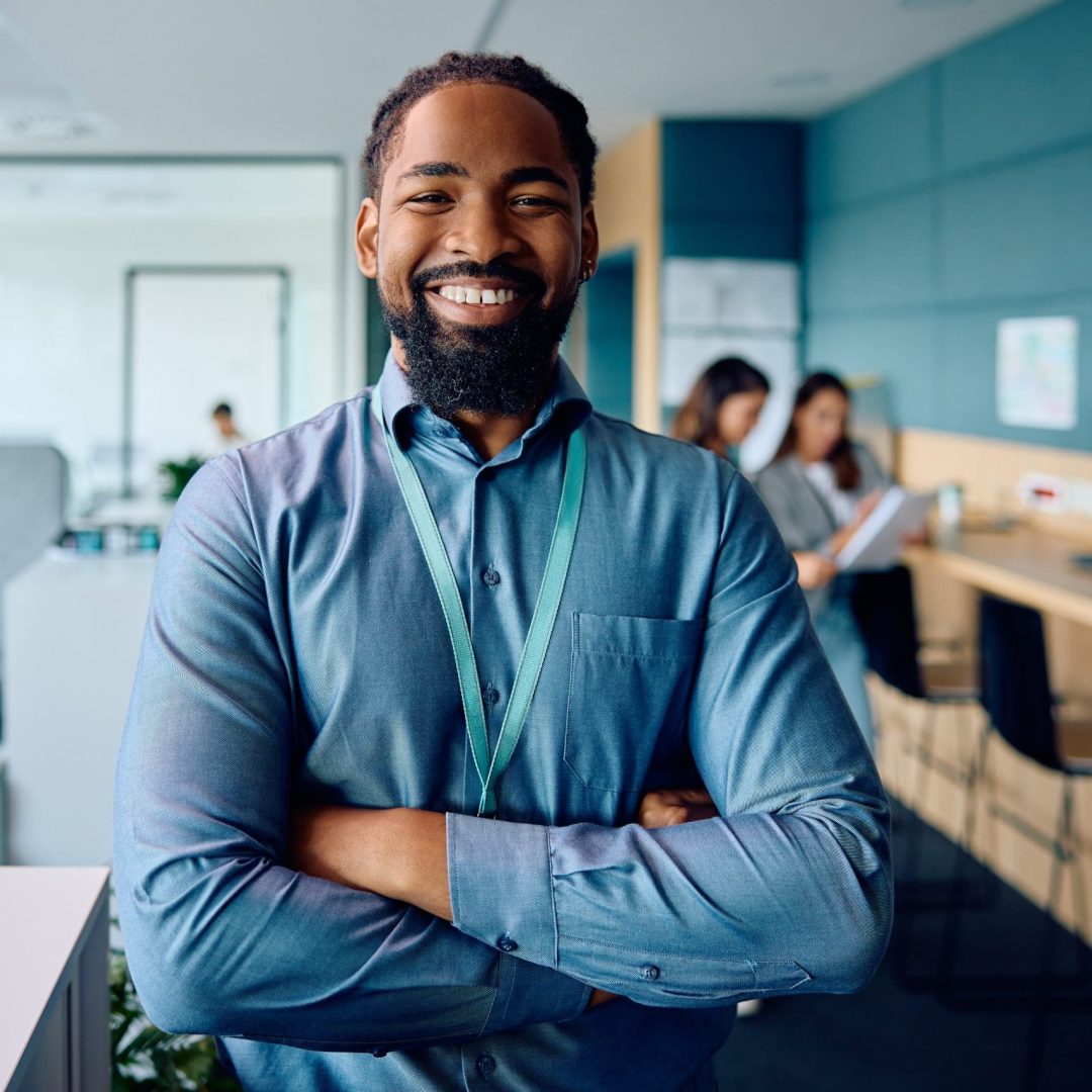 Happy African American businessman with arms crossed in the office looking at camera.