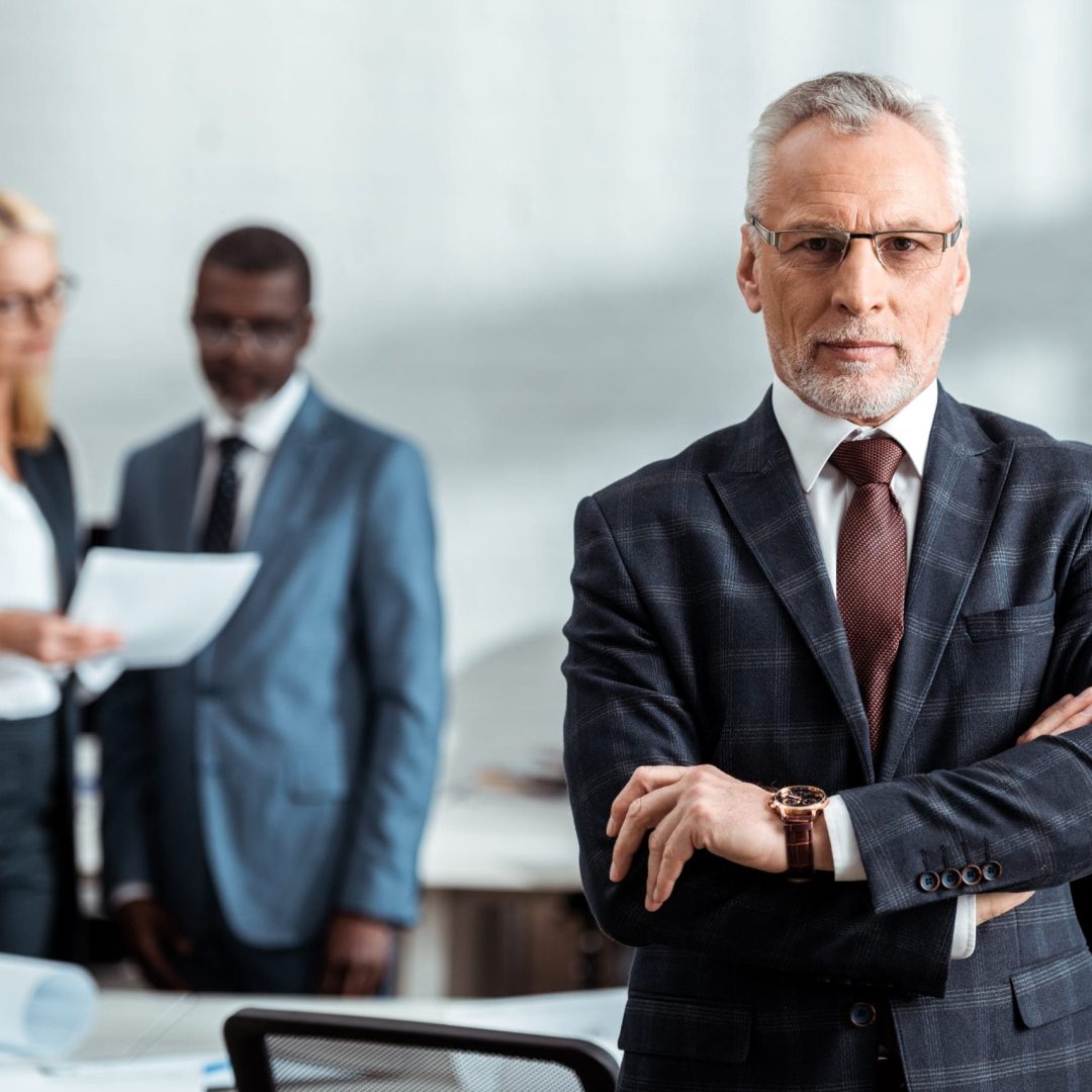selective focus of confident businessman in glasses and looking at camera while standing with