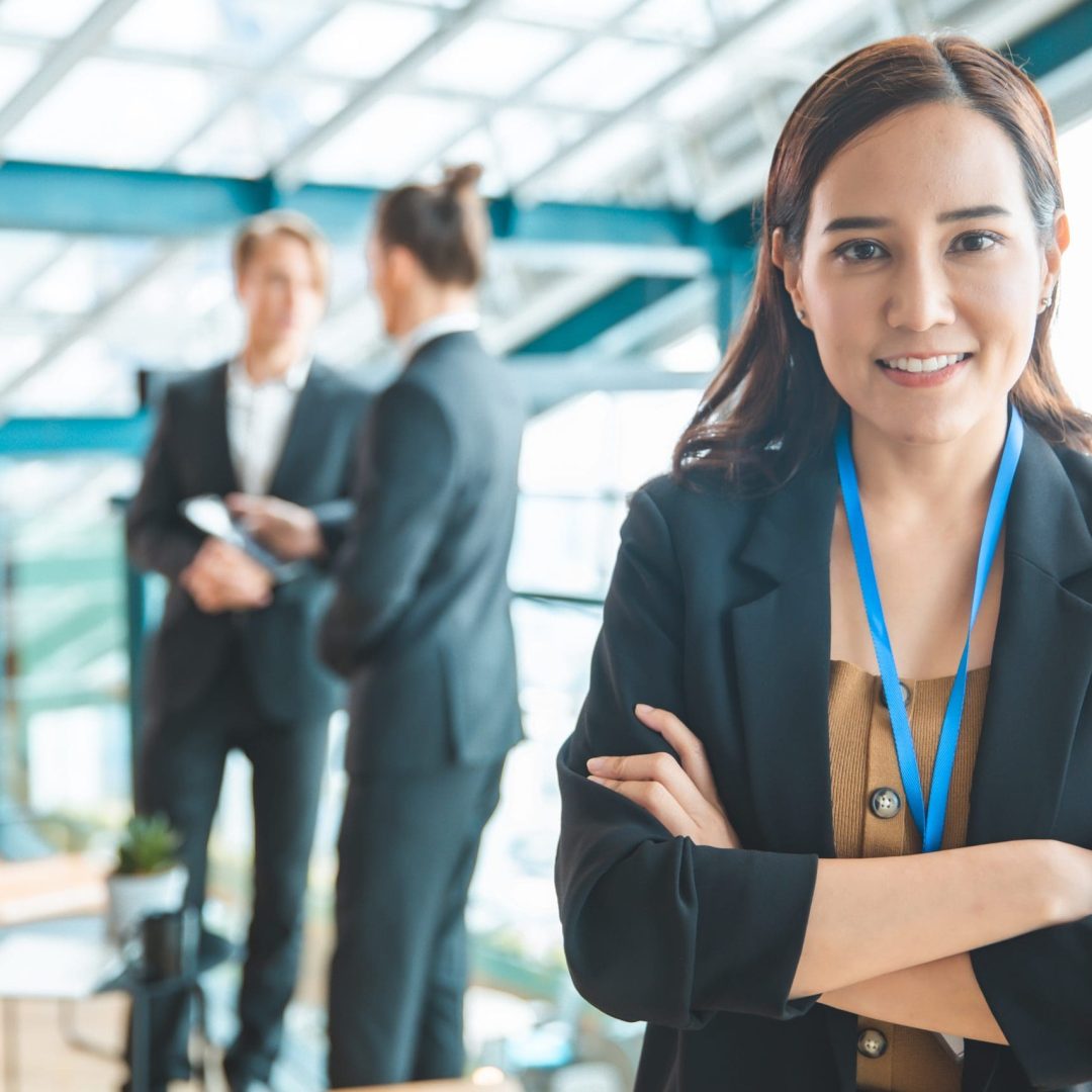 Business people applauding sitting at the table.Feeling confident in her  team. Happy businesswoman showing his  smiling while his colleagues standing in the background.